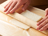 ラップを広げてパンを置き、麺棒を使ってのばすようにして、厚さを半分くらいにする。