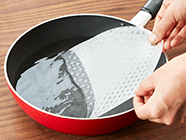 ボウル(フライパンもおすすめ)に水を張り、その中にライスペーパー1枚をくぐらせ、まな板の上に30秒ほど置く。その間に、プチトマト以外の野菜とハムを手前1/3のところに横長に置く。