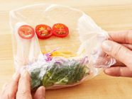 ライスペーパーが柔らかくなってきたら手前からひと巻きして、奥側にトマトを並べる。両端を折り込み、くるくると巻く。残りのライスペーパーも同様に、その都度1枚ずつ、水にくぐらせて巻く。