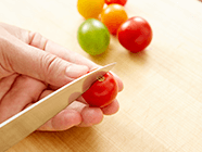 プチトマトのヘタを取り、ヘタ側に包丁で1ヵ所切り込みを入れる。