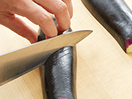 ナスはヘタを取り、縦半分に切り、皮の部分に斜めに切り込みを入れ、2cm厚の半月切りにする。赤ピーマンはヘタを取り、細切りにする。