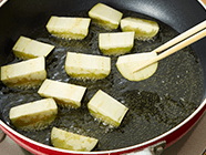 フライパンに1cm高さ程のサラダ油を入れ、ナスの皮部分を下にして揚げ焼きにする。他の面に返して全面を焼き、火が通ったら一旦取り出し、油を切る。