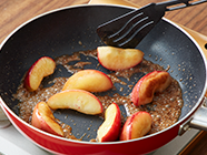 〈A〉をフライパンに入れて弱火にかけ、バターが溶けたらリンゴを並べて入れる。両面を各5分程焼いて、最後に中〜強火にしてバターがキャラメル色になったら火からおろし、砕いたアーモンドを加える。