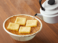 油あげをザルに広げ、熱湯(分量外)をかけ、油抜きをする。