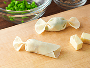 ギョウザの皮にグリンピース・ベビーチーズをのせ、お好みで黒こしょうを振る。
                                        ギョウザの皮の縁に水をつけ、3つ折りにして、両サイドを絞るように蛇腹に折る。