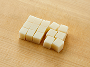 油あげは熱湯をかけて油抜きをして細めの短冊切りにする。戻したシイタケ・タケノコは薄切りに、ニンジンは細切りに、白ネギはみじん切りに、餅は1cm角に切る。