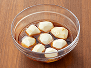 耐熱ボウルに〈A〉を混ぜ合わせ(1)を入れてラップをかけ、電子レンジ(500w)で約6分加熱し、サトイモの上下を返す。再び、電子レンジで約7〜8分加熱し、串が通ったらそのまま冷まして味を染みこませる。