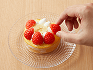 ロールケーキを横に寝かせ、中央にバナナを2切れ置く。周りに生クリームを絞り、その周囲にイチゴを並べる。