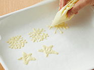 2段目にはバナナ1切れを中央に置き(3)と同様に生クリーム・イチゴをのせる。てっぺんにもイチゴをのせる。チョコプレートを置く場所に生クリームを少量絞り、チョコプレートをくっつけ、粉糖をかける。