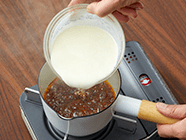 小鍋にグラニュー糖・水を入れて中火にかけ、鍋底を回しながらグラニュー糖を溶かす。縁から焦げて、中心までカラメル色になってきたら、一度火を止め、(1)の生クリームを少しずつ加える。