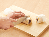 再度クッキングシートを巻いた状態にし、水で濡らした包丁で切り分けていくと、ご飯を潰さずにきれいに切ることができる。お好みで抹茶を彩りよく振りかける。